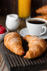 Croissants, coffee, orange juice and berries. Continental breakfast on wooden table