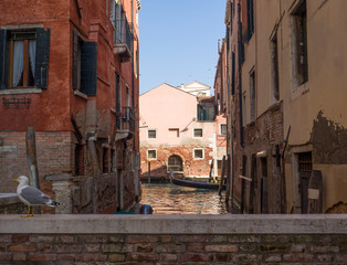 Obraz premium a gondola viewed from a small brick bridge in a canal of Venice, Italy