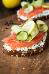 Smoked salmon sandwich with cream cheese and cucumber on wood