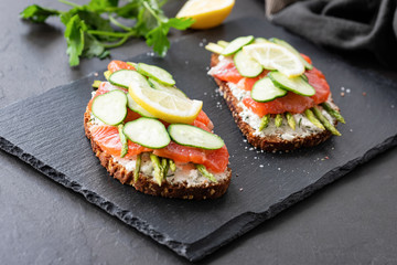 Appetizer sandwiches with salmon, asparagus, cucumber and cream cheese on slate
