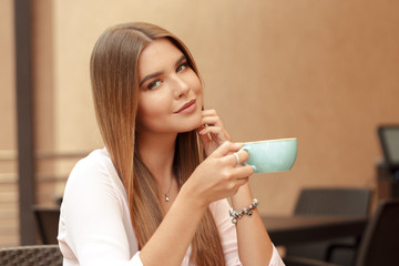 Young woman drinking coffee in a cafe outdoors