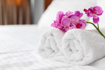 towels and flower on bed in hotel room