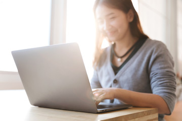 Portrait of a happy female using laptop computer in cafe. (Focus computer)