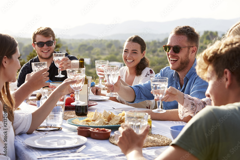 Wall mural group of young friends enjoying outdoor meal on holiday