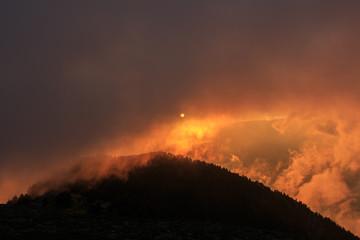 Reddish sun covered by clouds at sunset.Concept atmospheric phenomena