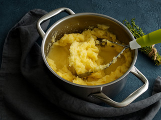 Mashed potatoes in bowl on dark stone blue table, rosemary, napkin, side view, close up