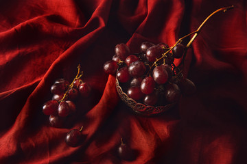 close-up shot of fresh grapes in vintage metal bowl on red drapery
