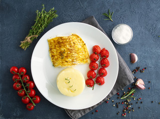 Fish cod baked in oven with mashed potatoes, tomatoes, diet healthy food. Dark gray background, top view