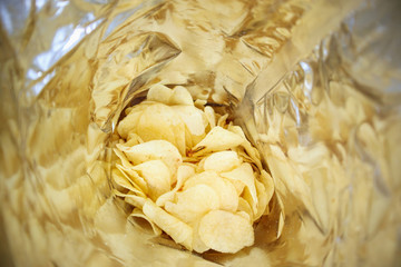 Potato chips in open snack bag close up