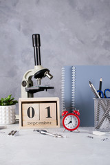 Back to school. Group of school supplies, red alarm clock, microscope and wooden calendar with date 1st September. Education concept