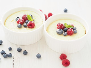 cheesecake decorated with raspberries, blueberries and mint in two ramekin, delicious dessert for breakfast, side view