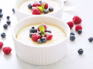 cheesecake decorated with raspberries, blueberries and mint in two ramekin, delicious dessert for breakfast, side view