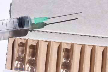 Novocaine in ampoule in the box and syringe on the table.
