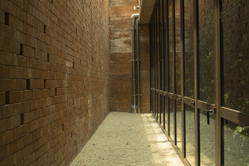 Obraz premium Background and texture of alleyway. Space between the brown brick wall and glass window.