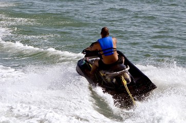 Angled overhead view of a man riding waves  on a black jet ski