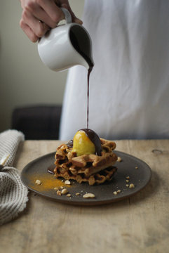 Midsection Of Woman Hand Pouring Chocolate Sauce On Waffle 