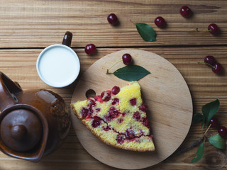 Home-made cherry pie on a wooden table with a mug of milk