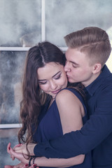 love story. a young guy gently hugs his girl in blue clothes against the stained-glass window