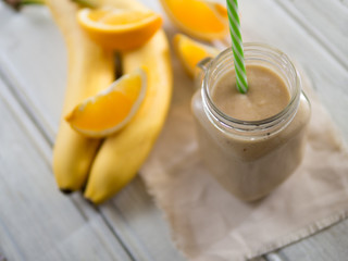 fresh summer milkshake or orange and banana smoothie on wooden white table. top view