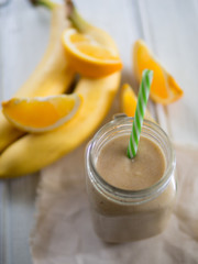 Fresh banana and orange smoothie on wooden white table