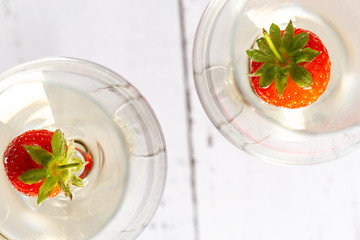 Two wine glasses with white wine and strawberry.