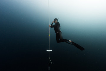 Student freediver learns presure equalization being on a depth and holding a rope