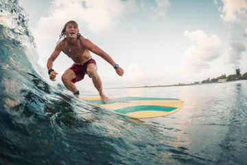 Young surfer rides ocean tropical wave