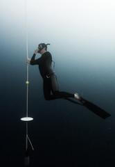 Student freediver learns presure equalization being on a depth and holding a rope