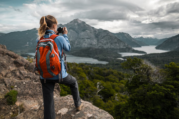 Tourist hiker with red backpack takes pictures of the valley with mountains and lakes. Patagonia,...