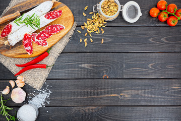 Sliced cured sausage with spices and a sprig of rosemary.