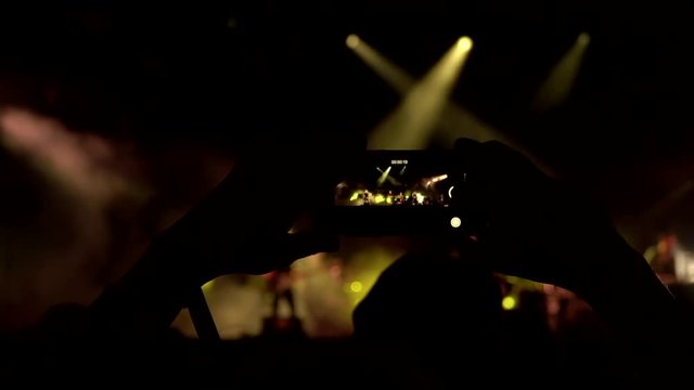Concert rock band filmed on the phone. At night at a music festival. close-up of the phone, in the background scene and concert