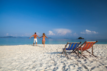 Young couple runs into tropical sea at sunny day