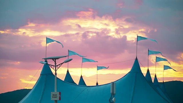 In the wind fluttering flags on the circus tent against the beautiful evening sky at sunset