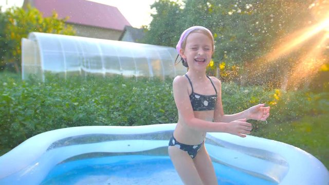Little girl is swimming and jumping in the garden pool
