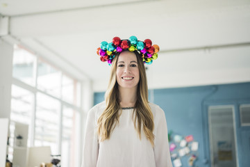 Portrait of smiling woman with colorful Christmas bauble wreath on her head