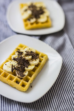 Waffle garnished with banana and chocolate shaving on plate