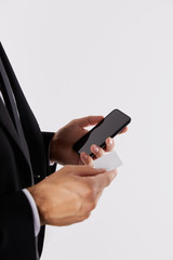 cropped image of businessman holding empty business card and smartphone with blank screen isolated on white background