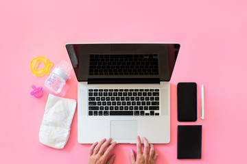 Working mom top view flatlay of workplace baby items and laptop with phone