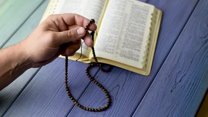 Prayer, meditation with God. A man's hand holds a rosary over the bible.