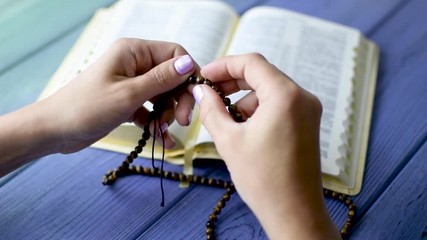 Prayer, meditation with God. A female hand holds a rosary over the bible. - Powered by Adobe