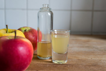 immune defense boosting, skin clarifying, detoxing natural apple cider vinegar on wooden kitchen table with ripe apples as decoration
