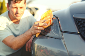 close up of man cleaning car with microfiber cloth.