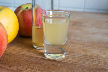 apple cider vinegar in glass with apples as decoration on wooden table