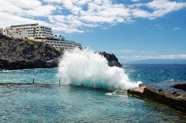 Big ocean wave breaking on the natural outdoor swimming pool in the resort town of Los Gigantes ("Cliffs of the Giants"). Municipality Santiago del Teide, Canary Islands, Tenerife, Spain   