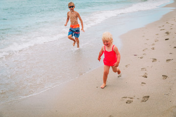 little girl and boy run play have fun at beach