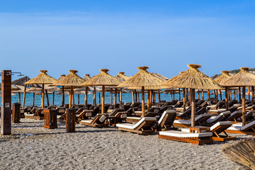 The beach with straw umbrellas from the sun and soft sun loungers. Adriatic coast. Summer. Without people.