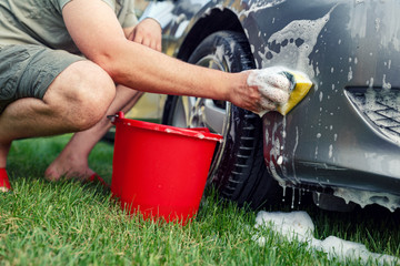 Sponge and bucket – male washing his car. © Lucky Fenix