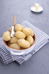 Young boiled potatoes with butter in a cup. Towel and gray background. Delicious vitamin summer dinner. Copy space.