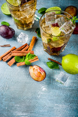 Summer iced refreshment drink. Cinnamon and plum lemonade cocktail, with fresh lime and mint, blue background copy space