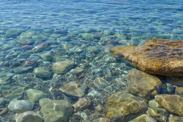 Naklejka na ściany i meble Marine background. Quiet Adriatic Sea. Blue clear water and large stones.